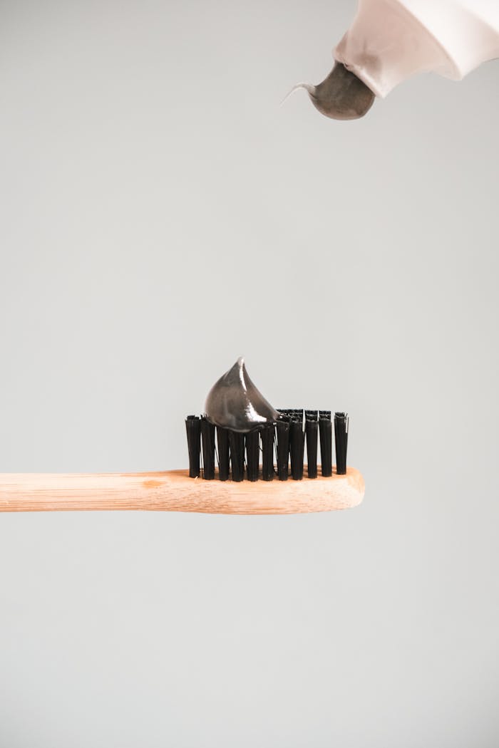 A bamboo toothbrush with charcoal toothpaste set against a neutral background, emphasizing eco-friendly oral hygiene.